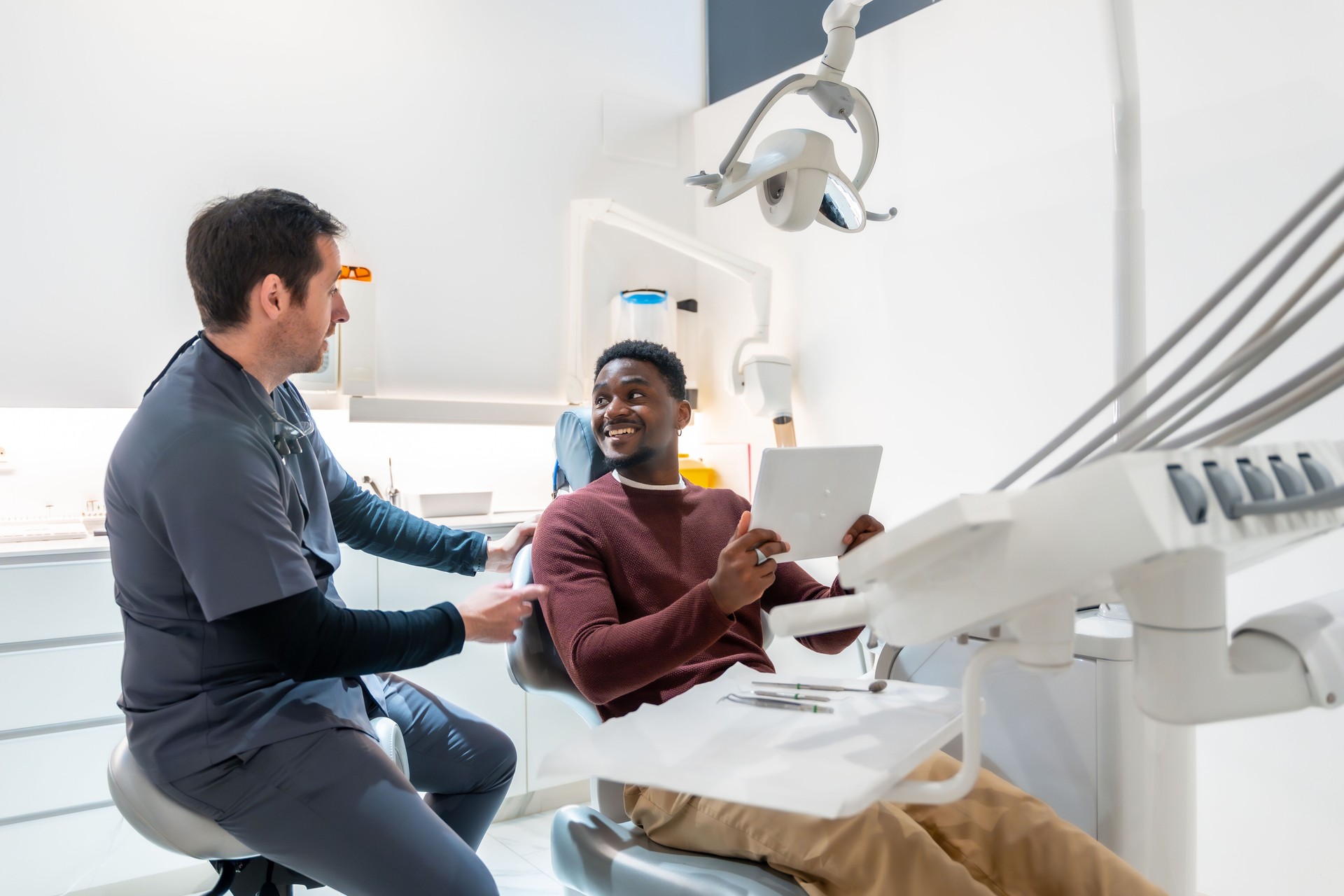 Dentist showing results on tablet to patient in dental clinic